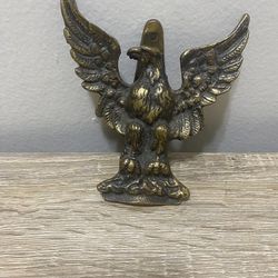 A vintage door knocker in the shape of an eagle, usually made of brass.