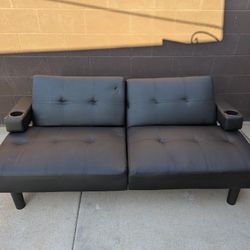black leather futon with cup holders on each end 
