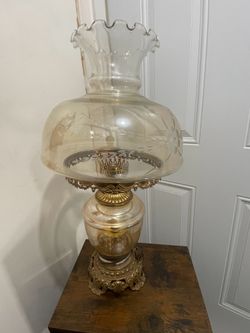 vintage hurricane table lamp features an amber glass shade with a ruffled top and etched floral designs.