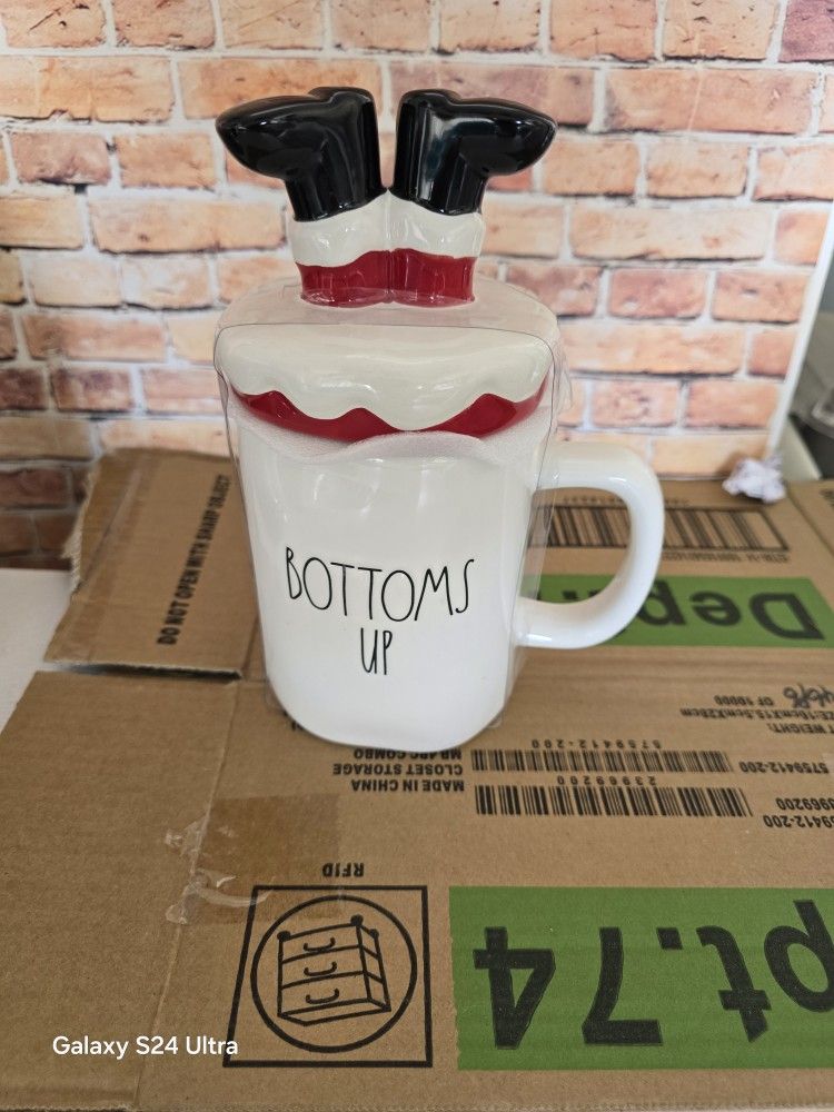 Get into the Christmas spirit with this unique and contemporary Rae Dunn mug. The "Bottoms Up" design features Santa's boots/feet upside down on a red