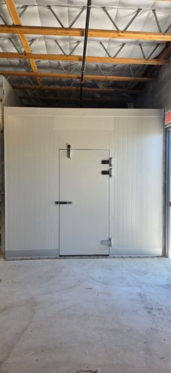 10’ x 17’ x 9’ commercial walk-in cooler/freezer with insulated panels and a hinged door all in white.