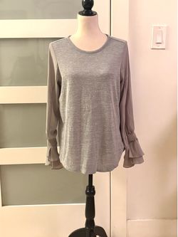 Grey long-sleeved blouse with ruffled cuffs and round neck, brand DG2 by Diane Gilman, size medium.