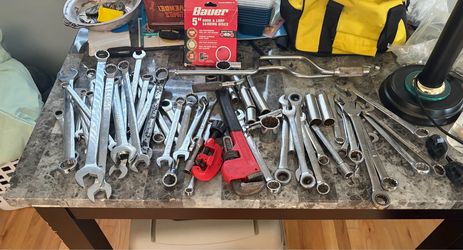 variety of hand tools, including combination wrenches, a pipe wrench, and sockets., speed handles