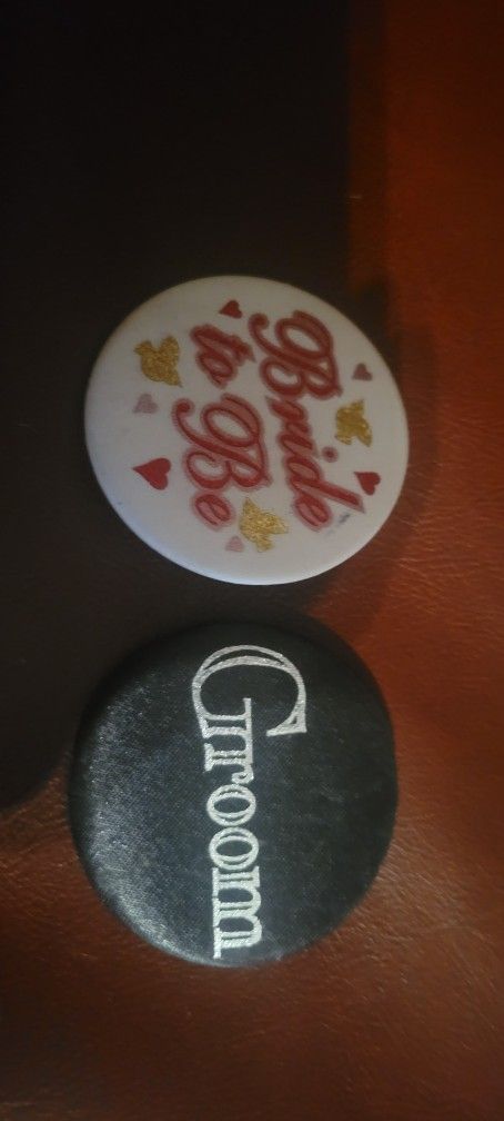 Buttons, two circular pins or badges, one white and one black, typically worn to celebrate a wedding or engagement events