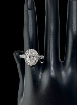 Oval-cut diamond halo engagement ring in a white gold Setting with a pave band.