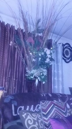 Tall vase with flowers arrangements in it