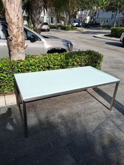 Modern dining table features a sleek stainless steel frame and a frosted glass top W62" D36" H29"