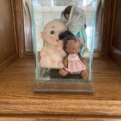 Cutie doll in glass case with two other dolls