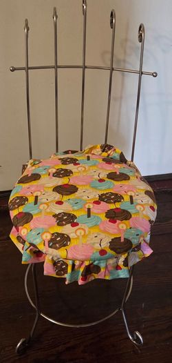 metal vanity chair features a round seat cushion covered in a colorful cupcake-patterned fabric.