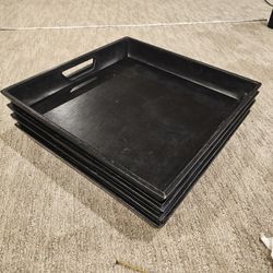 4 black, leather like covered ottoman serving trays with handles. 