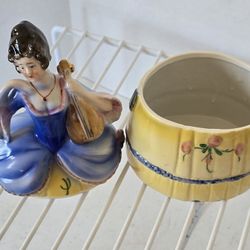 VTG Porcelain Trinket / powder box. Lady with yellow & Blue dress holding a chelo 