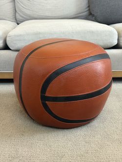 Basketball design ottoman  orange and black leather-like upholstery. 19 inches wide 14 inches tall.