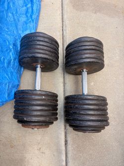 Heavy-duty pro-style dumbbells are a pair with black cast iron weight plates and knurled chrome handles.