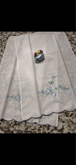 White cotton napkins with delicate blue floral embroidery. Scalloped blue-edge hem. Elegant, lightweight and perfect for dressy tables. Soft pastel ac