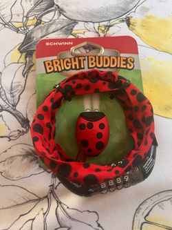 This image shows a Schwinn Bright Buddies bicycle accessory set featuring a red ladybug-themed LED light and a matching patterned combination lock.