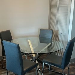 Glass top dining table with 4 grey chairs