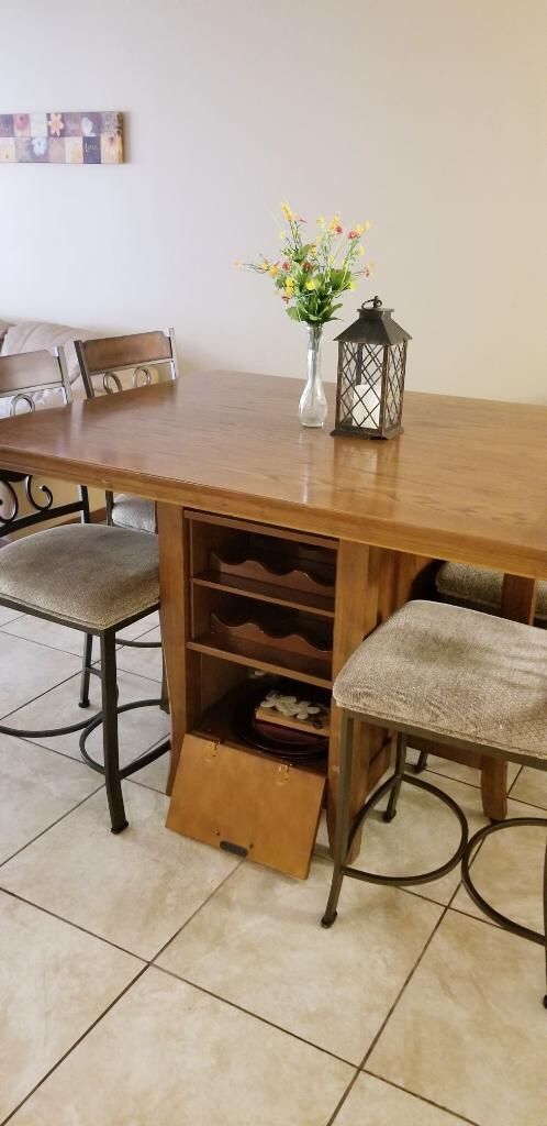 Brown dining table with built in wine rack and chairs