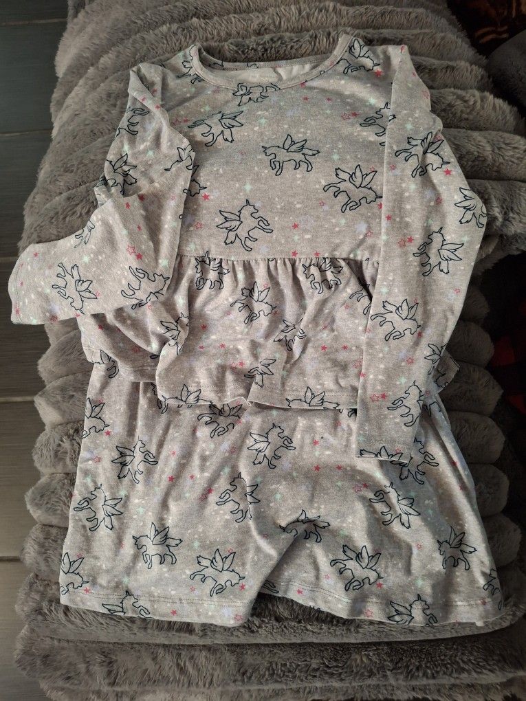 Cozy and adorable unicorn print dress for kids. Features a soft gray fabric with playful unicorn designs. Perfect for a comfortable play date!