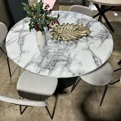 Brand new Modern round marble-look dining table + 4 grey chairs. Black fluted base. Four light grey upholstered chairs included.