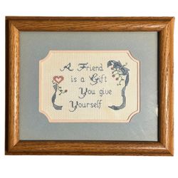 Vintage framed needlepoint sampler with the quote “A Friend Is a Gift You Give Yourself.”