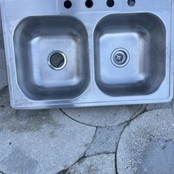I 2-hole sink in good condition measures 33 inches long, 22 inches wide, 8 inches deep, each hole measures 14 inches