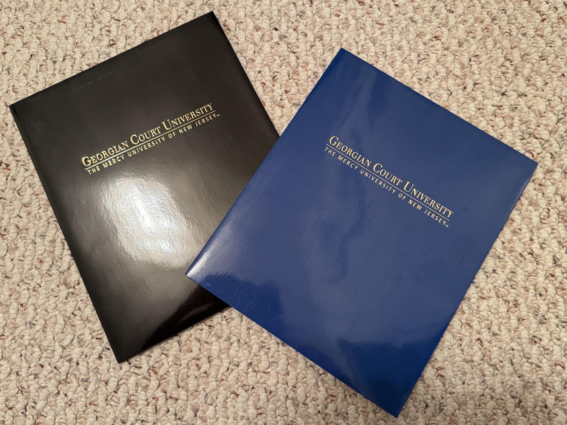 2 New Georgian Court University logo pocket folders. Black & blue