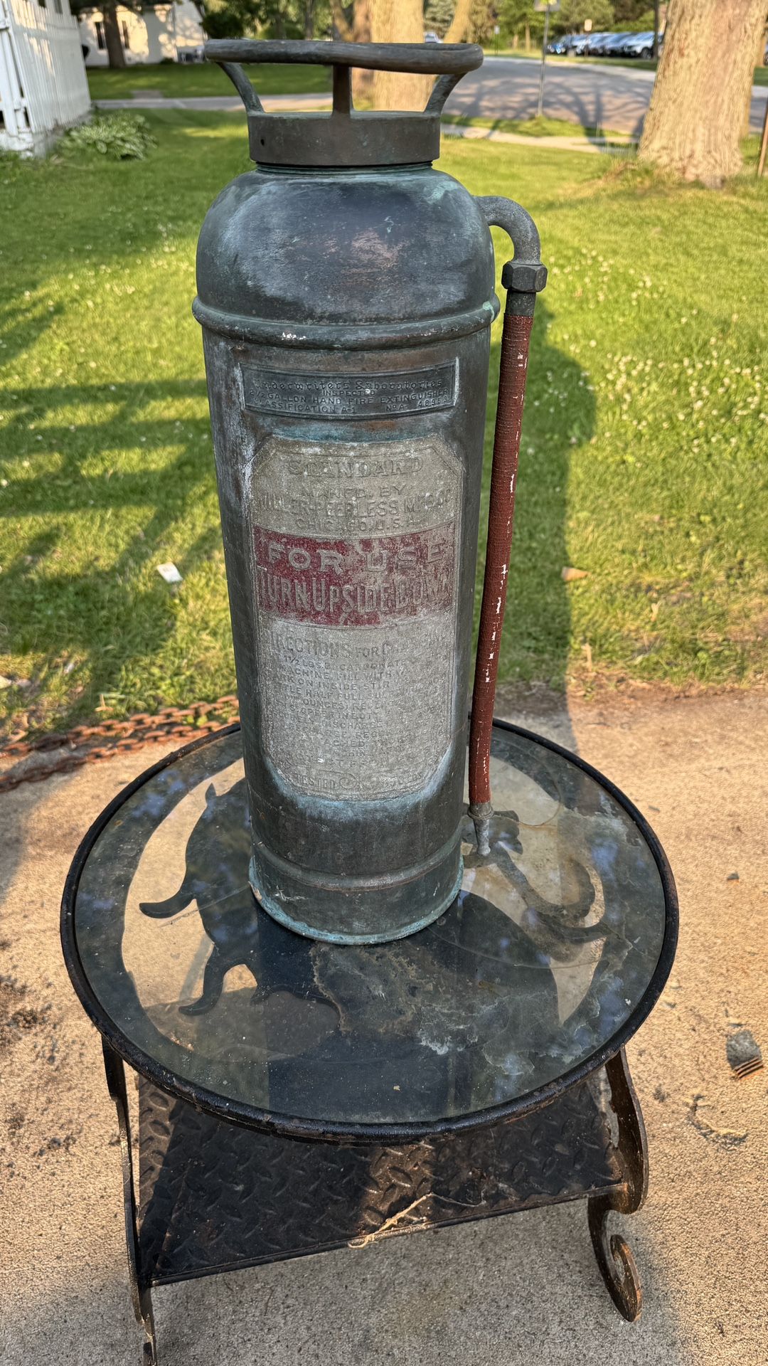 vintage Miller-Peerless fire extinguisher, likely from the 1920s, made of copper and brass. It is a hand-pump type water extinguisher, designed to be