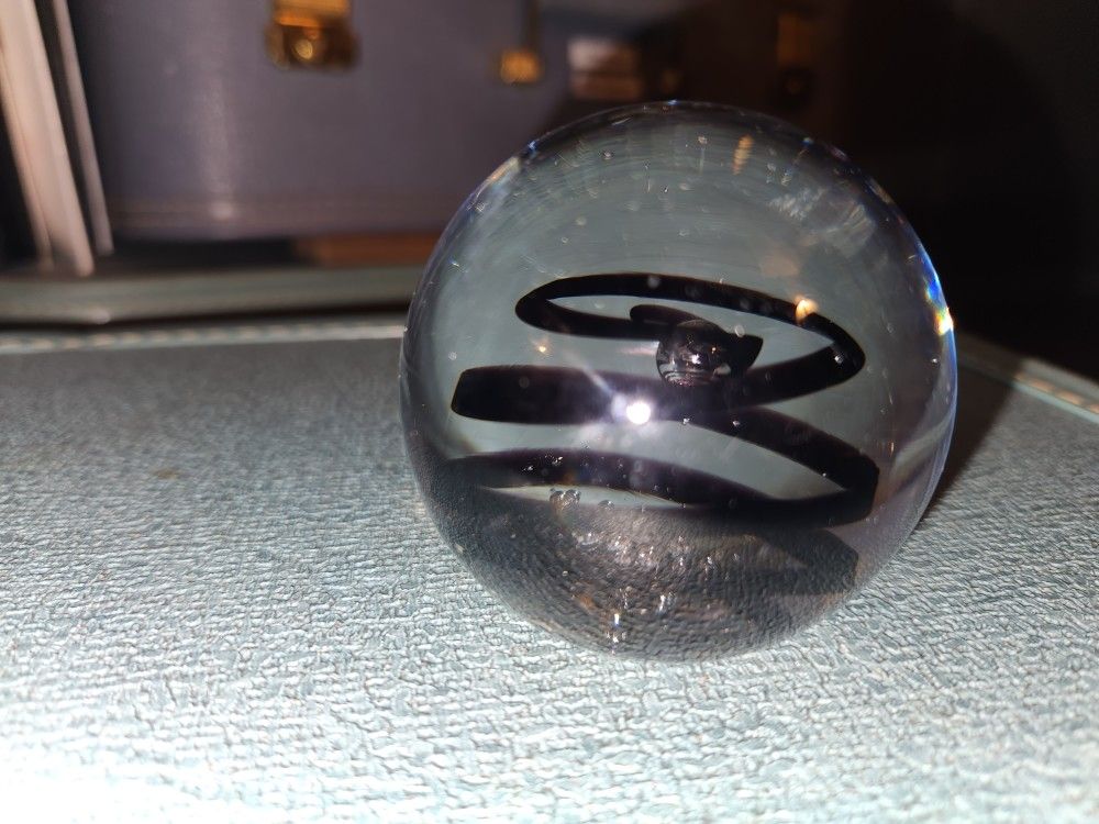 Glass art paperweight decor.
Clear with black swirls inside