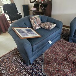 Comfortable blue sofa with two patterned cushions.