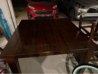 Expandable wood tall dinner table with 6 leather chairs from Ashley furniture