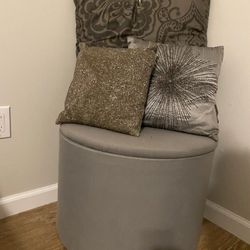 Round gray storage ottoman with pillows