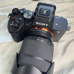 Great Sony Alpha 7 IV camera. Has the FE 28-70mm f/3.5-5.6 OSS lens. Lens includes a hood.