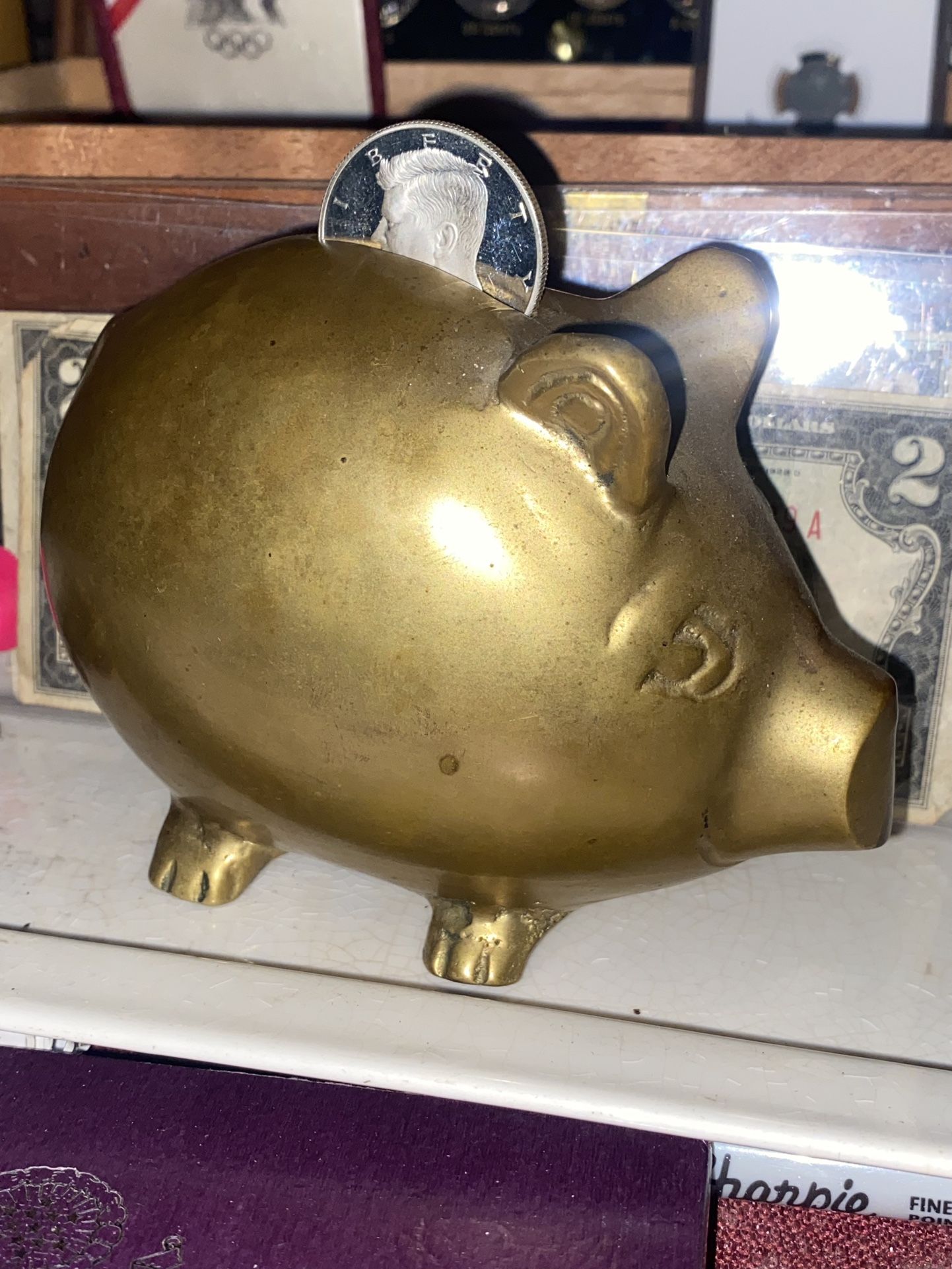Vintage brass piggy bank with a 2004 proof silver half Kennedy coin