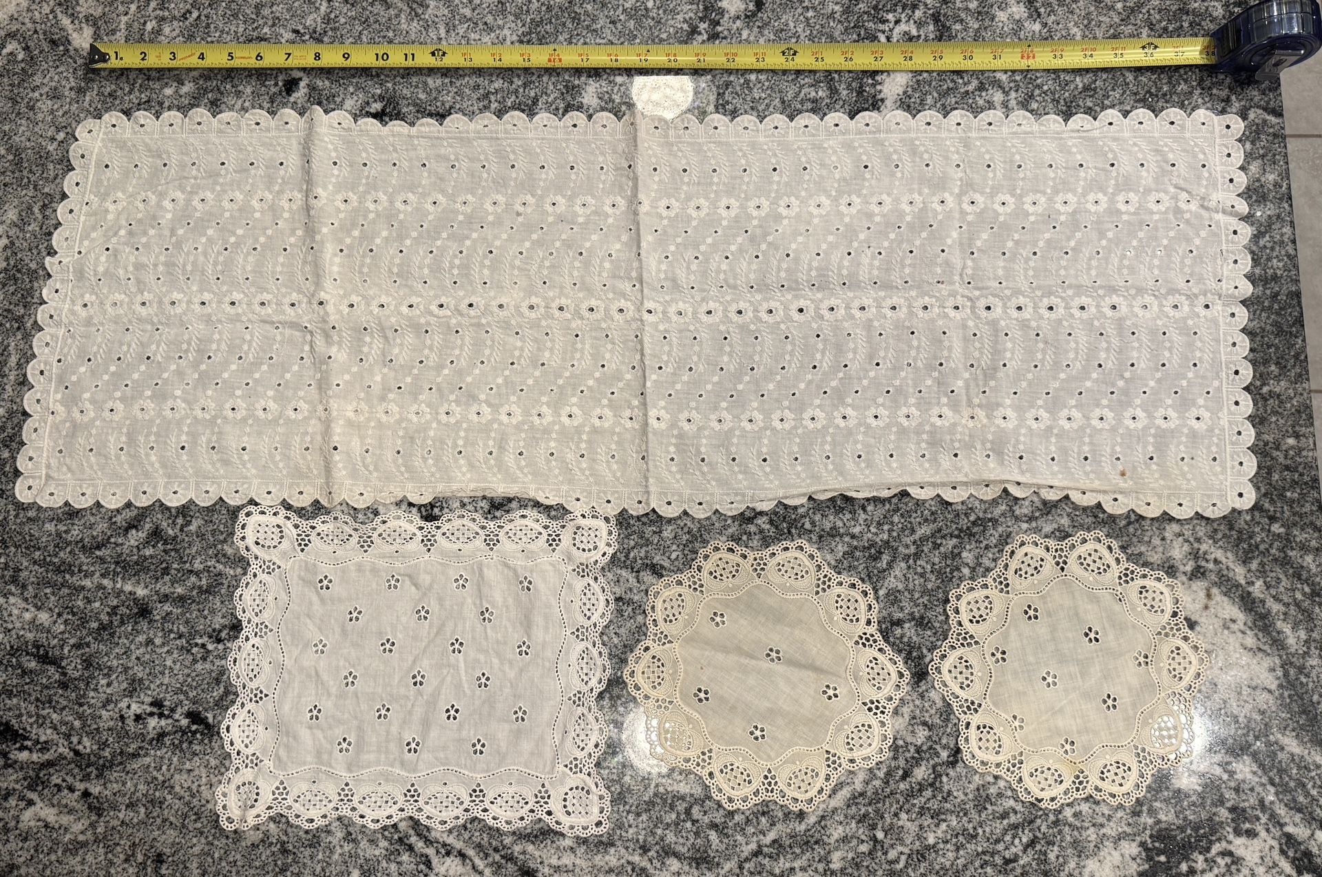 Vintage lot of 4 pieces of eyelet lace. Table runner approximately 38” long. Some small stains and 1 seam coming apart in the table runner.
