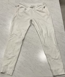 Comfortable white jogger pants with drawstring and zippered pockets.