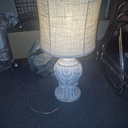 Naomi table lamp featuring a distressed white finish with gold accents, mimicking an antique finial.