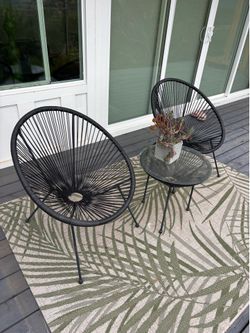 Set of two black Acapulco chairs and small table with rug