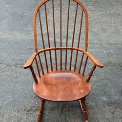 Vintage wooden rocking chair with spindle back and armrests. Classic Windsor style, made of solid hardwood with a warm brown finish. In good condition
