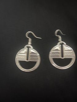 Elegant silver-toned drop earrings with a geometric circular design. These earrings feature intricate engraved patterns including zig-zags and horizon