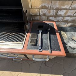 Outdoor stainless steel gas grill station with side burner and storage drawers.