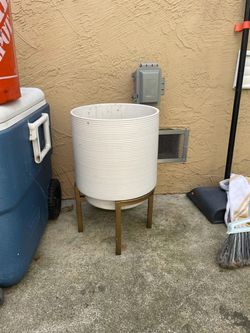 white, ribbed metal planter is elevated by a slender gold stand