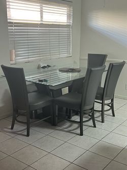 Like-new glass dining set with 6 gray chairs; barely used and very beautiful.