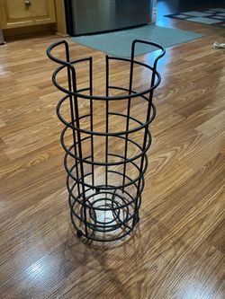 matte black freestanding wire-frame toilet paper reserve featuring an open-concept cylindrical design with raised bottom