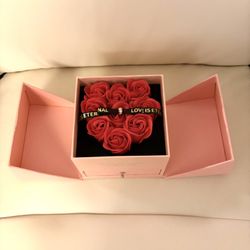 This item is a pink gift box with 9 artificial red roses arranged in a heart shape, designed for Valentine's Day or as a jewelry gift.
