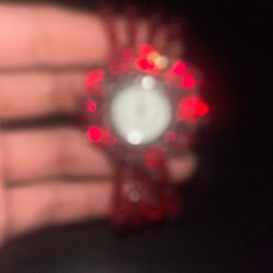 This item appears to be a handmade red beaded bracelet featuring a central flower-shaped brooch component decorated with rhinestones