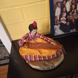Oriental Doll Playing Instrument On Cushion