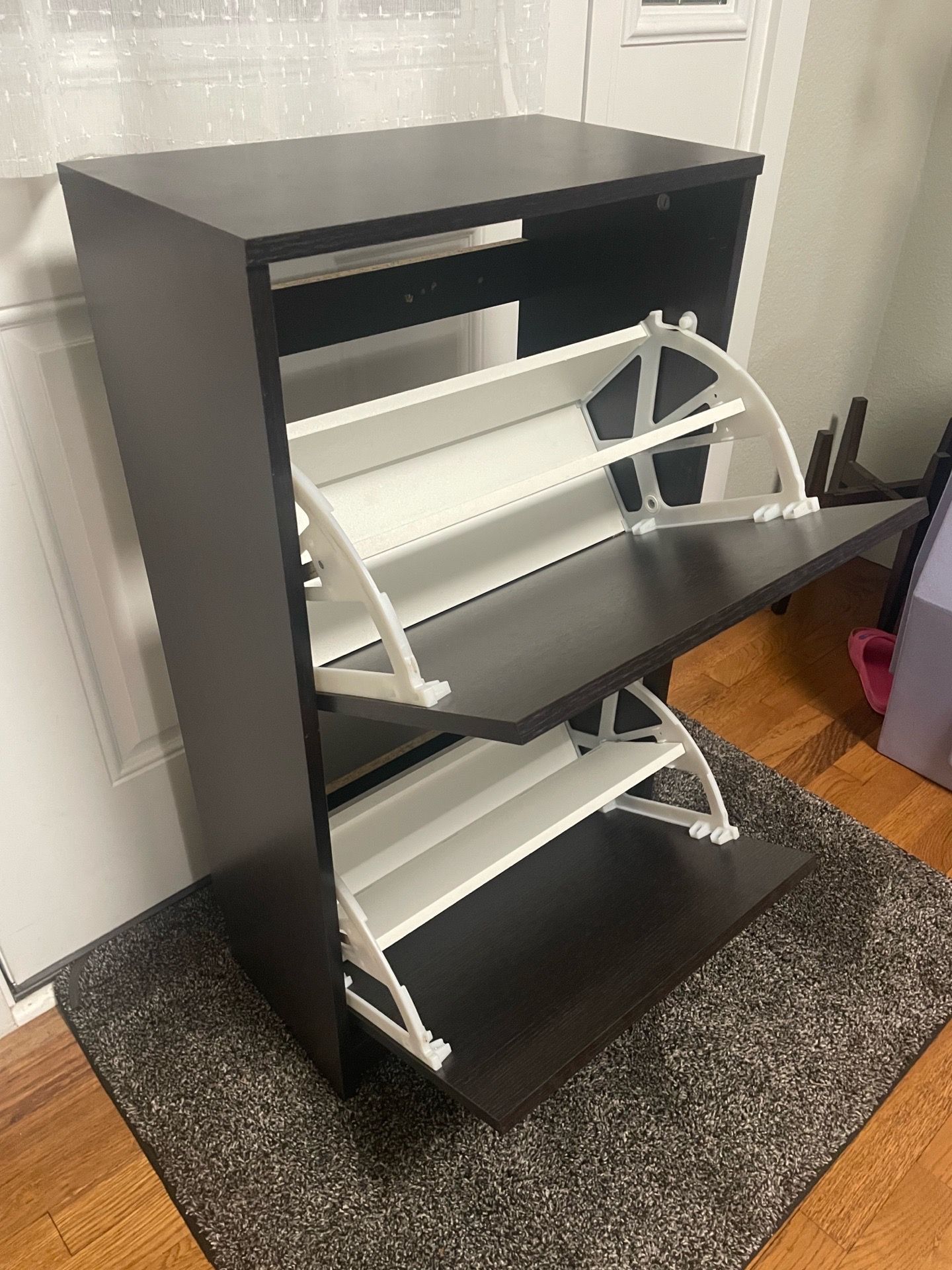 Stylish shoe cabinet is dark brown. It has two tilt-out drawers. Each drawer has white shoe racks inside. Great for organizing shoes in entryway or be