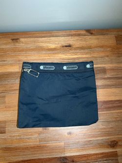 This blue LeSportsac cosmetic bag features a branded strap in the signature gray and a silver zipper pull.