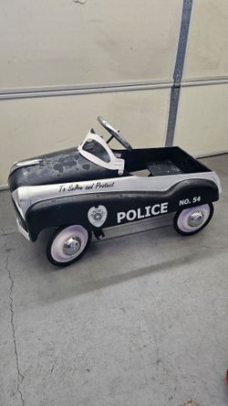 The image shows an InStep "Metro City's Finest" No. 54 Police Pedal Car, a black-and-white steel  Pressed steel body with white-wall wheels and a chro