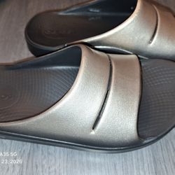This is a pair of OOFOS Women's OOahh Luxe Slide Sandals Gold Brown 